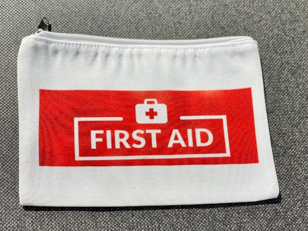 A Glamping Essentials original first aid pouch. Shown here is the "First Aid" side with bold red printing indicating this, the reverse has the Glamping Essentials logo. The pouch zips up to store all your hiking essentials.