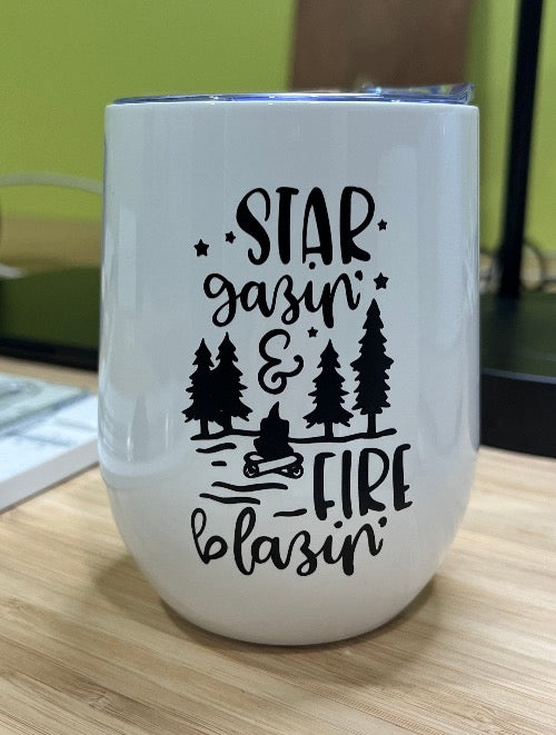 Our insulated wine tumbler in white with  'star gazing' & fire blazing' in black including a campfire and four tall trees.  Lots of stars