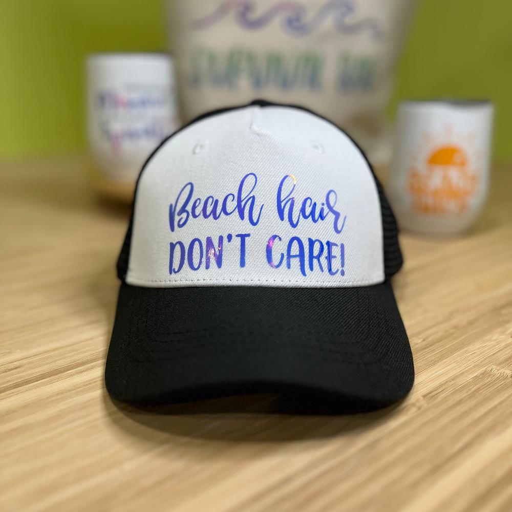 Black trucker cap with white front, blue holographic "Beach Hair don't care!"