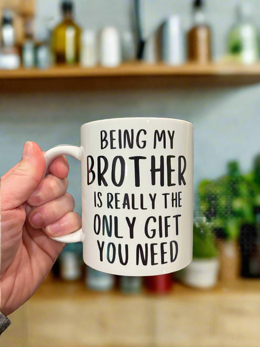 White ceramic mug with the custom wording "Being my brother is really the only gift you need" in bold black font