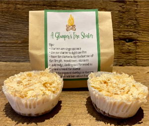 Our Glamper's Fire Starters.  Made of soy wax and pine shavings, there are two pictured here in front of their paper bag with instructions.