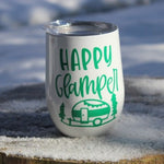 Load image into Gallery viewer, Our Glampy Wine Tumbler. The wine tumbler is white with the saying &quot;Happy Glamper&quot; printed on it in green. The tumbler is peacefully sitting on a snow covered wooden stump, livin&#39; it&#39;s best glamping life.
