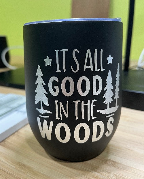 Our insulated wine tumbler in black, with the words 'it's all good in the wood' in silver font.  three tall trees and two stars