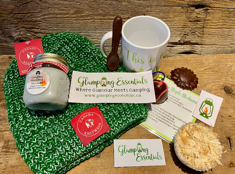 Everything that came in the April "Cozy by the Campfire" box: a candle, a toque, a ceramic mug, dark hot chocolate bomb, dark hot chocolate spoon and dark chocolate sunflowers, glampers fire starters, drink recipe, magnets and stickers.