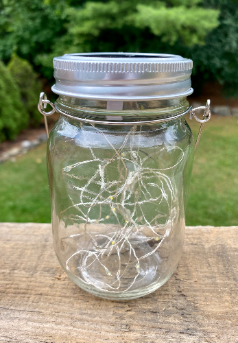 Pictured here is a solar lantern made from a mason jar and fairy lights.  It has a silver lid and thin metal band to hand it from a tree, clothesline or whatever you need to hang it from.  A true Glamping essential.