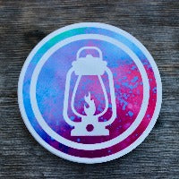 Round ceramic coasters, 100% customizable. This one has a green / blue / pink / purple tie-dye background with a white icon of a lantern in a white circle.