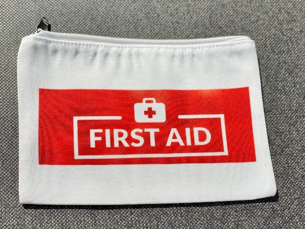 A Glamping Essentials original first aid pouch.  Shown here is the "First Aid" side with bold red printing indicating this, the reverse has the Glamping Essentials logo.  The pouch zips up to store all your hiking essentials.