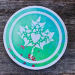 Load image into Gallery viewer, Round ceramic coasters, 100% customizable. This one has a mosaic of hearts making up a maple leaf in white over a green/blue tie-dye background.
