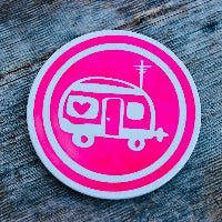 Round ceramic coasters, 100% customizable. This on is bright pink with an icon of a small RV in a white circle.